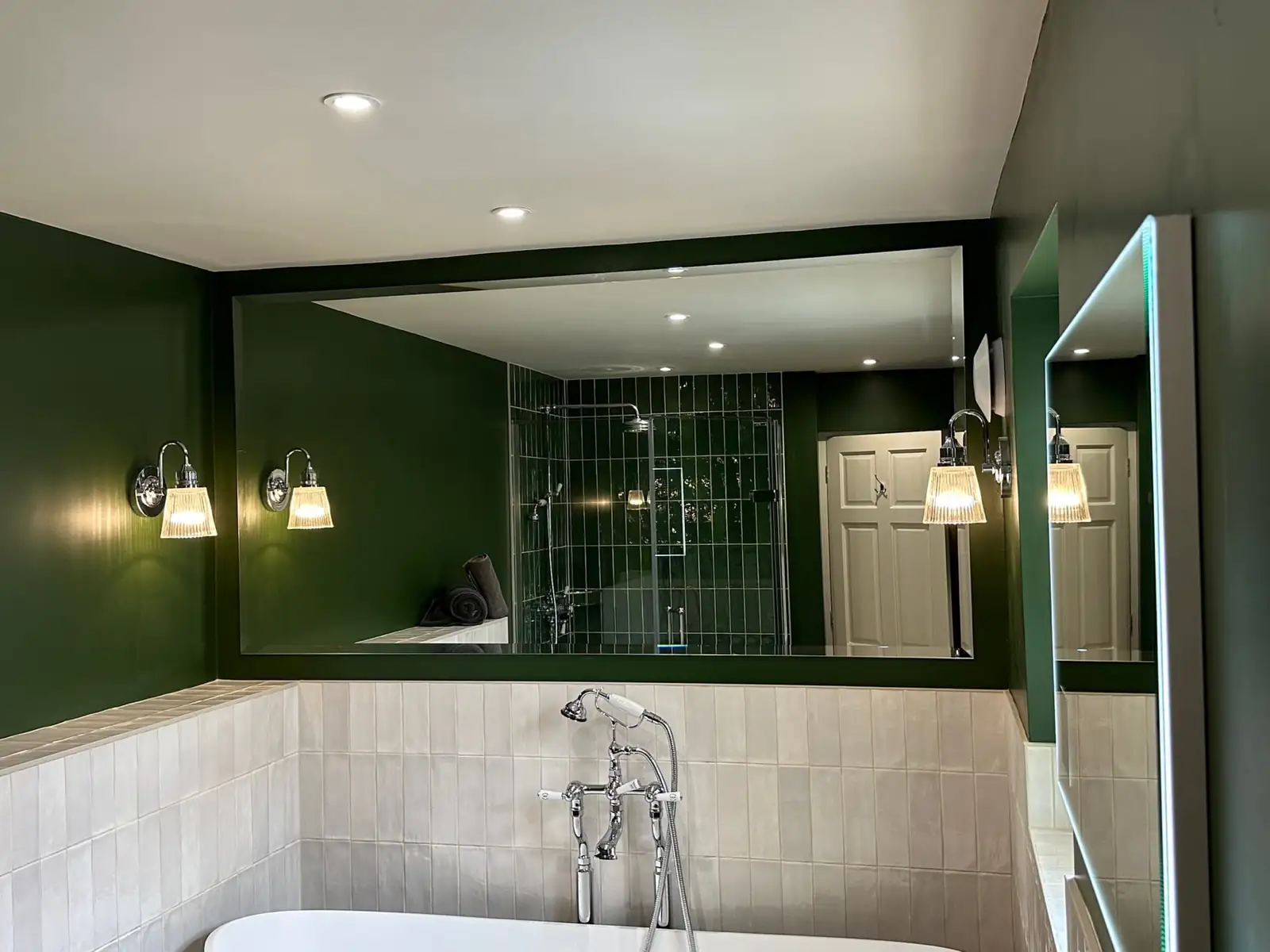Renovated bathroom with a freestanding bath, green walls and a bespoke mirror