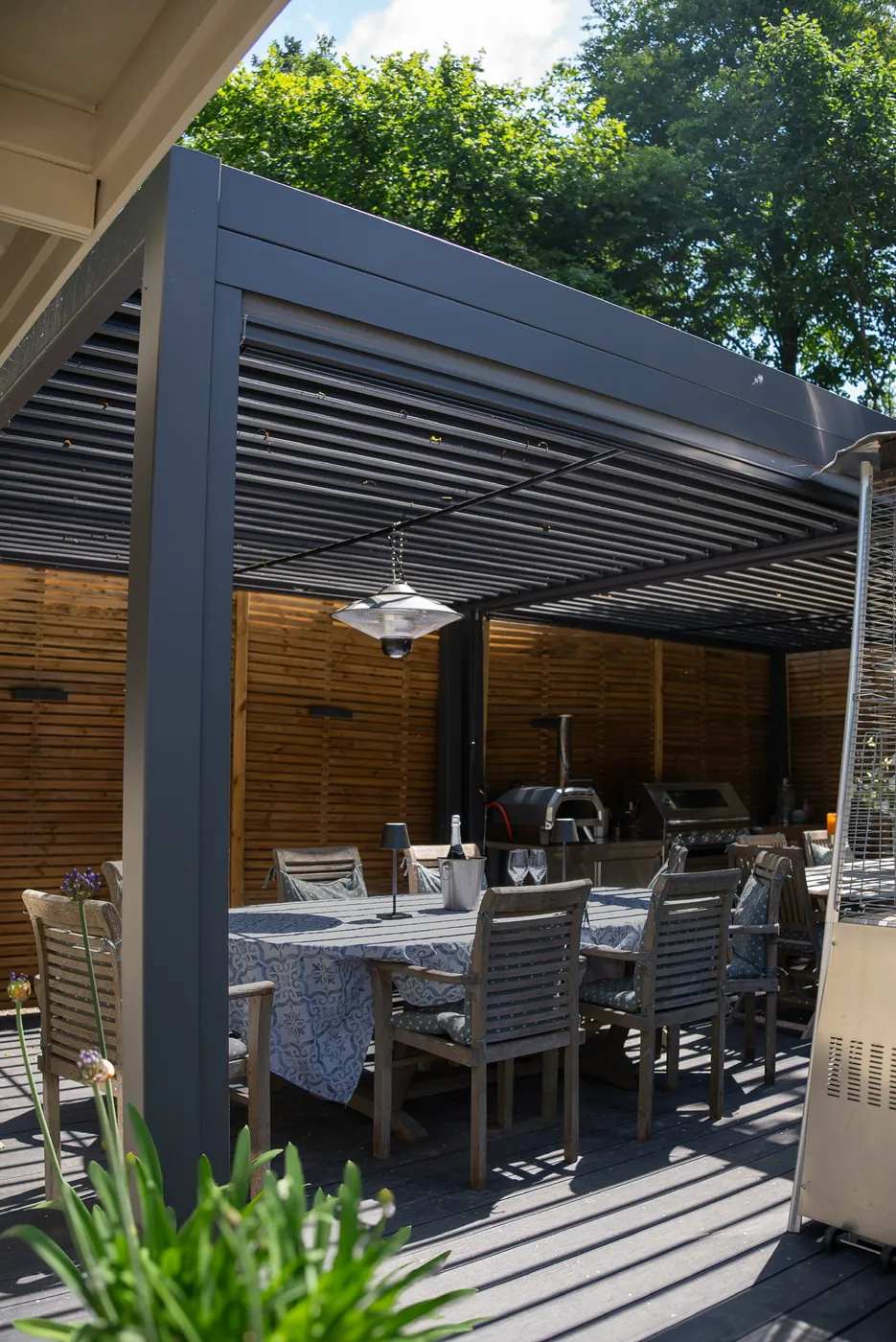 Louvered pergola over an outdoor kitchen and dining area