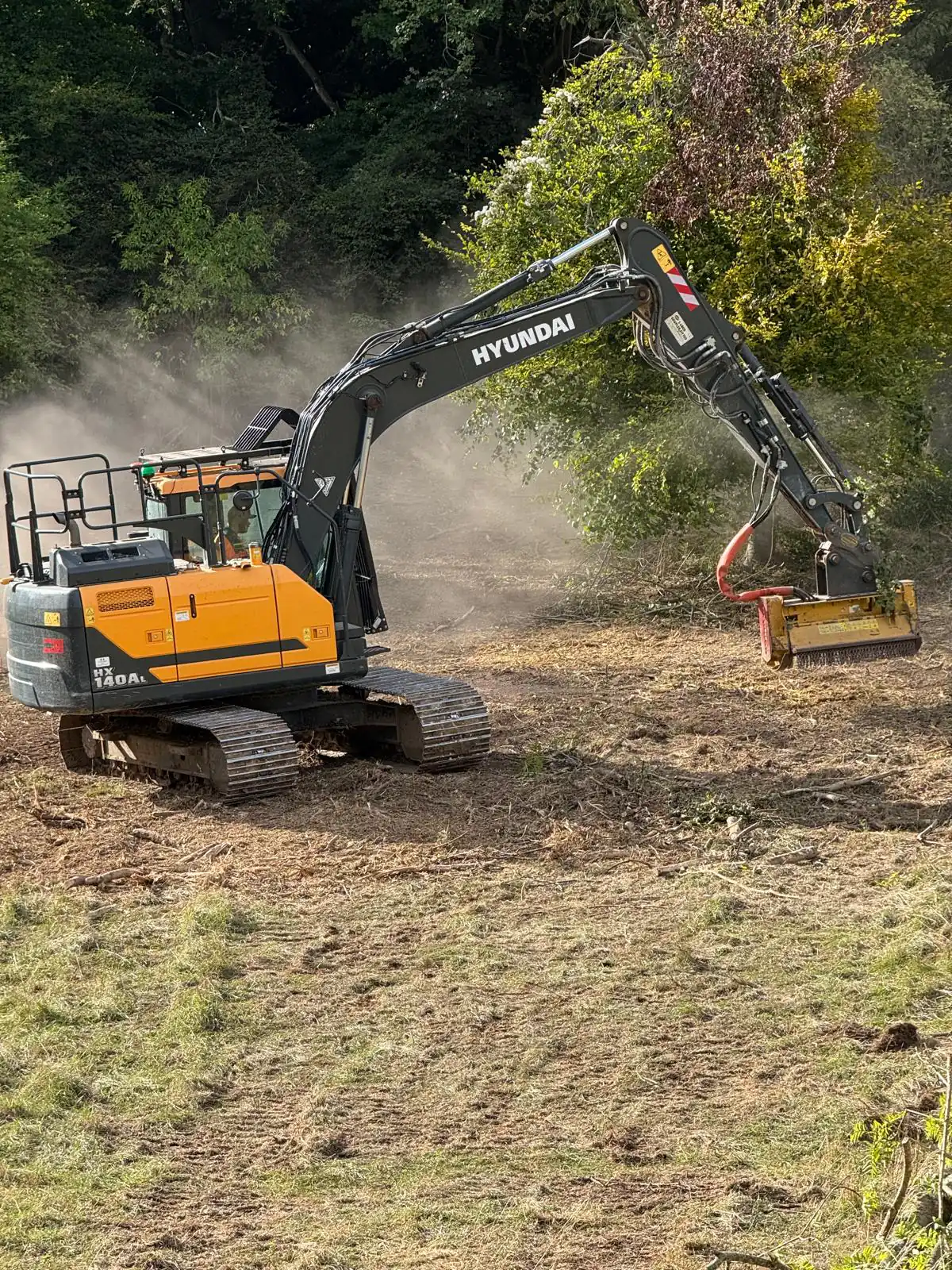Risdon excavator mulching trees on a clearance site, dust rising