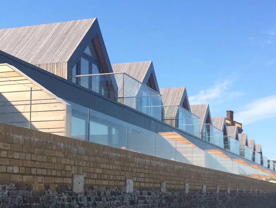 Frameless glass balustrades along a row of timber-clad gabled homes
