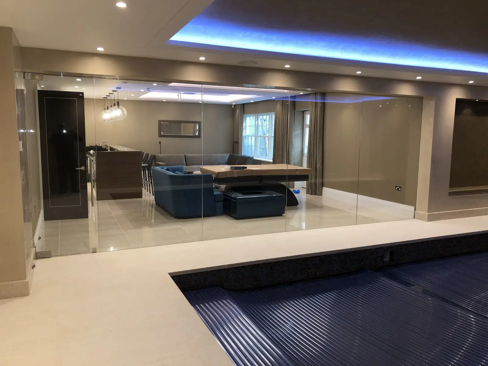 Glass wall beside an indoor pool, with LED ceiling lighting and downlights