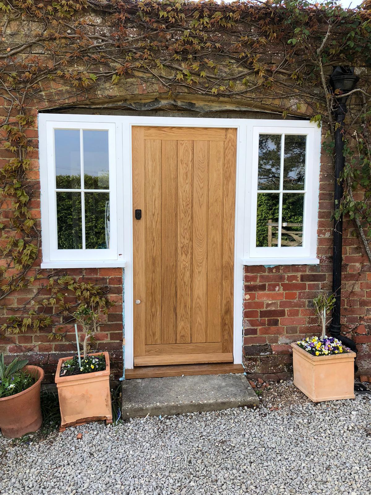 New oak door and cottage windows set into an old brick wall