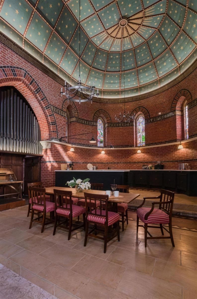 Long dining table under the painted dome and organ pipes of a converted chapel