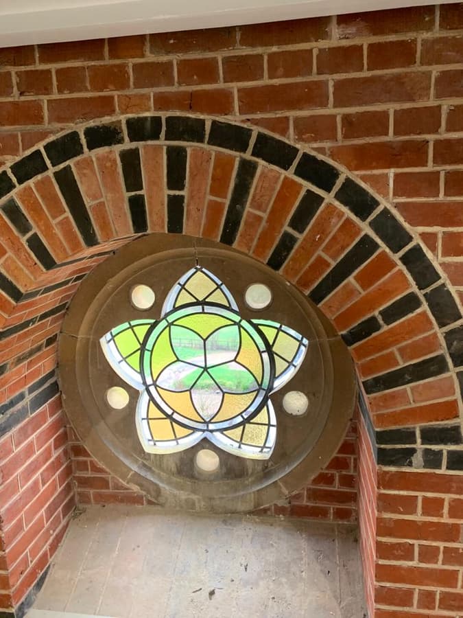 Stained glass rose window set in a patterned brick arch