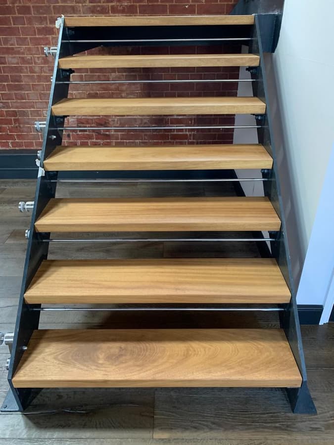 Oak treads on a black steel staircase against brickwork