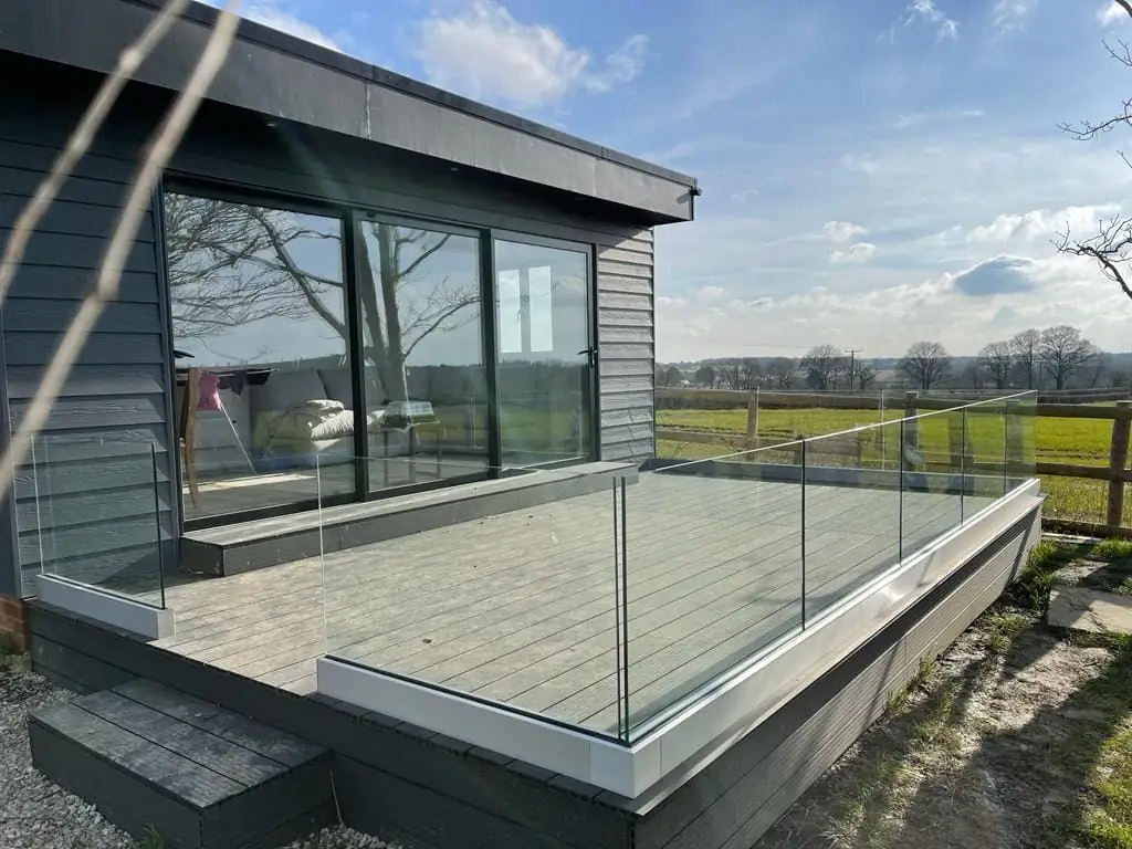 Dark-clad garden room with a glass-balustraded deck