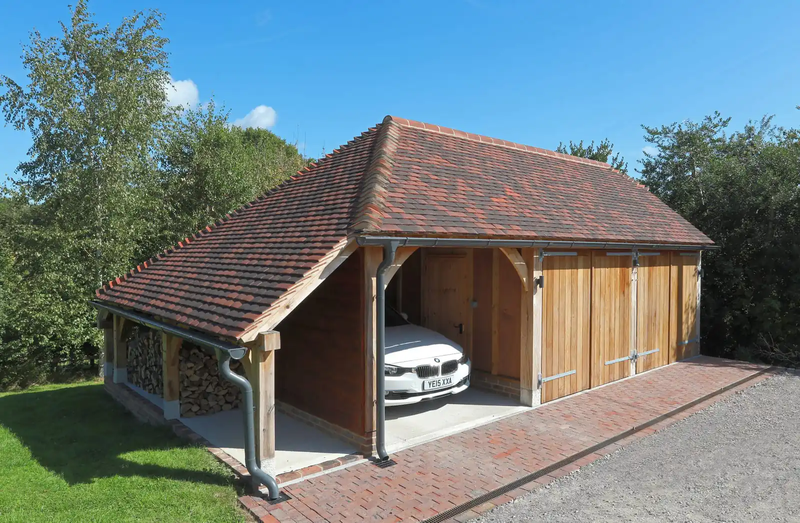 Oak framed garage with an open bay, oak doors, a log store and a clay tiled roof