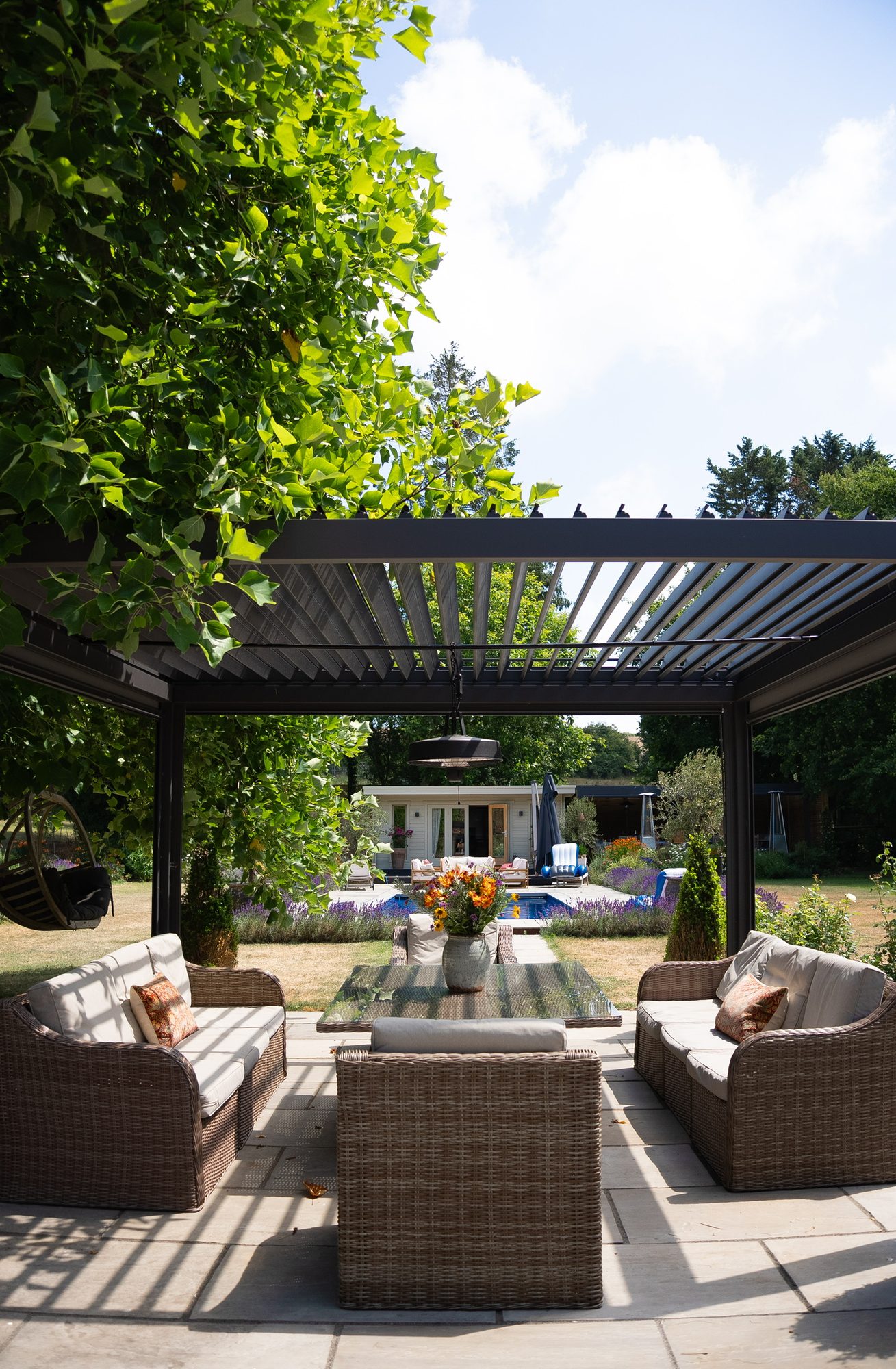 Louvres open on the poolside pergola, the pool and garden office beyond