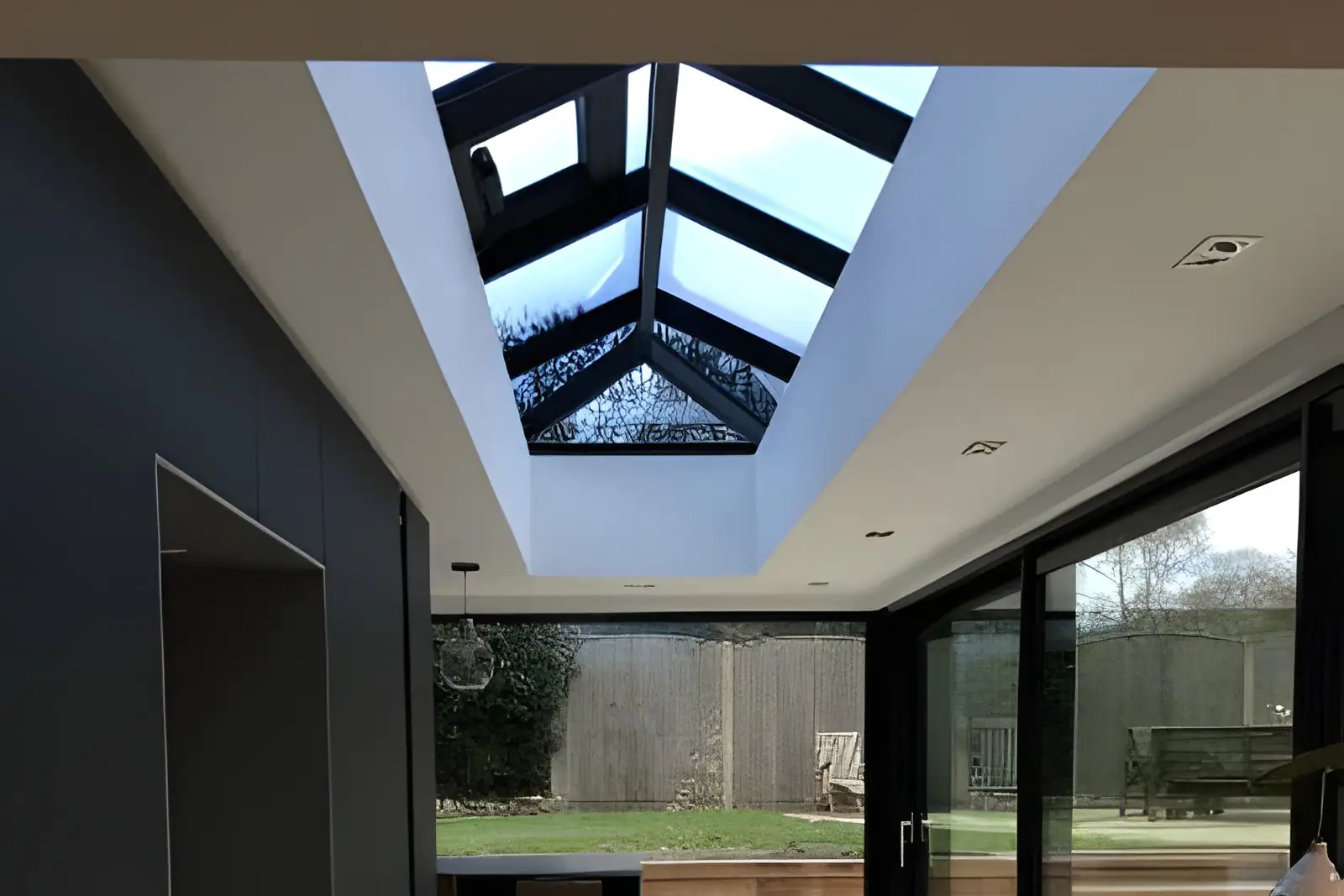 Black-framed roof lantern over a modern kitchen extension with sliding doors to the garden