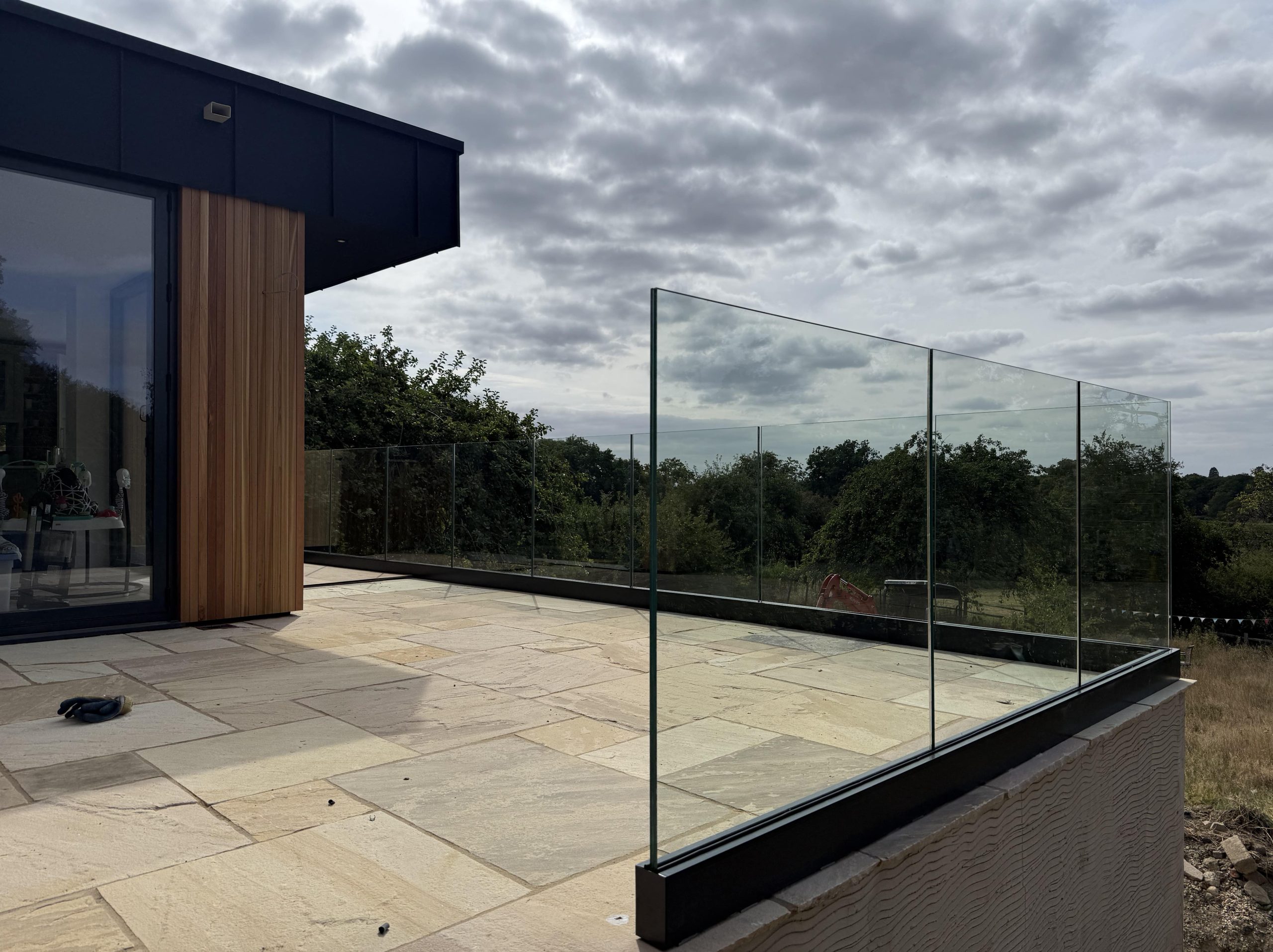 Frameless glass balustrade on a cedar-clad garden room terrace